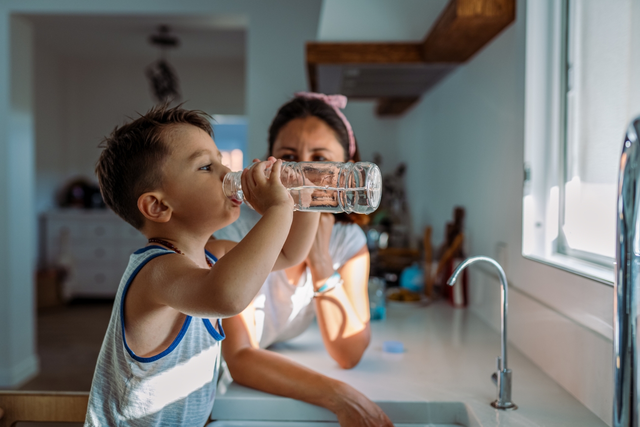 boy drinking water at kitchen sink